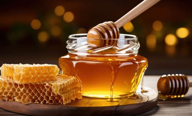 honey dripping from dipper into jar set against wooden tones 11533552591