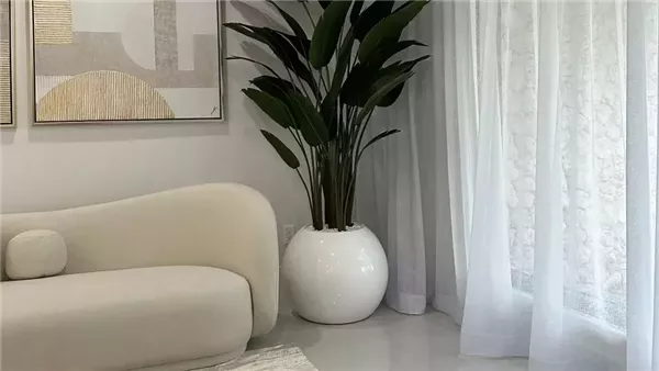 "تصميم داخلي لغرفة معيشة عصرية تعكس أحدث صيحات الديكور 2026، تتميز بأثاث ذو خطوط منحنية وألوان ترابية دافئة، مع دمج النباتات الطبيعية في الجدران وإضاءة شمسية ناعمة تتخلل الستائر الكتانية، توفر أجواء من الرفاهية الهادئة والاستدامة."