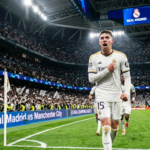 "نجم ريال مدريد فيديريكو فالفيردي يصرخ محتفلاً في مباراة مانشستر سيتي بدوري أبطال أوروبا 2026، مع خلفية تظهر لوحة النتيجة في استاد سانتياغو برنابيو وشعار موقع الحريفة."