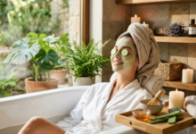 "امرأة تستمتع بجلسة عناية بالبشرة داخل حوض استحمام، تضع ماسك طين أخضر طبيعي وشرائح خيار على عينيها، مع وجود أدوات العناية مثل العسل والصبار والشموع في أجواء هادئة تدل على الراحة والنضارة."