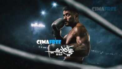 "مشهد درامي متوتر من مسلسل علي كلاي الحلقة 22 يجمع بين الشخصيتين منصور الجوهري وألمظ في مكتب فخم قاتم، يتبادلان نظرات الغضب والمؤامرة بعد علمهما بتنازل العوضي عن الأرض لروح، مع وثائق عقد على المكتب."