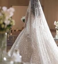 "عروس عربية شابة تتألق بإطلالة أنيقة في العيد، تجلس في مجلس منزل عصري مزين بديكورات العيد، تستقبل الضيوف بابتسامة وتقدم القهوة والحلويات التقليدية في أجواء عائلية دافئة."